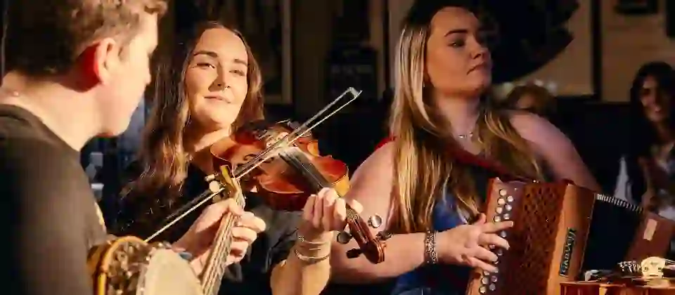 Traditional Irish music session at Kelly’s Cellars in Belfast with musicians playing fiddle, banjo and concertina.