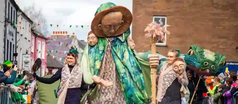 Een reusachtige figuur in een groene mantel leidt de St. Patrick’s Day-optocht door de straten van Kilkenny, waar de toeschouwers langs de route staan.