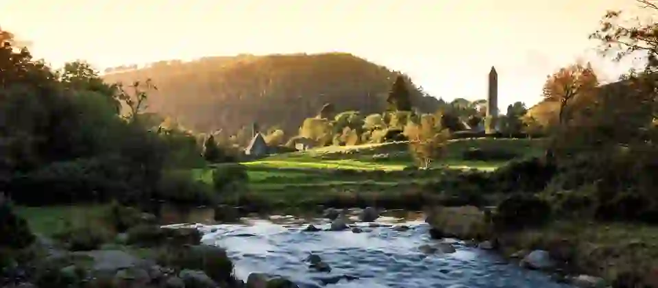 Herfstkleuren rondom de monastieke ronde toren en het bovenste meer in Glendalough, county Wicklow, Ierland.