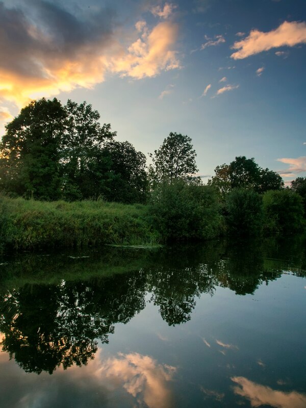 Coucher de soleil doré sur le Lough Neagh avec des eaux calmes et des collines lointaines.