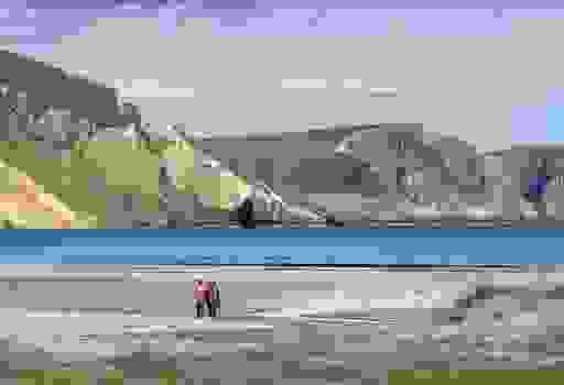 Una coppia cammina lungo la spiaggia di sabbia di Keem Bay, incorniciata da alte scogliere e dalle calme acque blu dell'Atlantico.