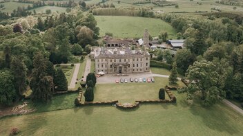 Aerial view of Hilton Park Estate in County Monaghan surrounded by lush woodland with cars parked along the front drive.