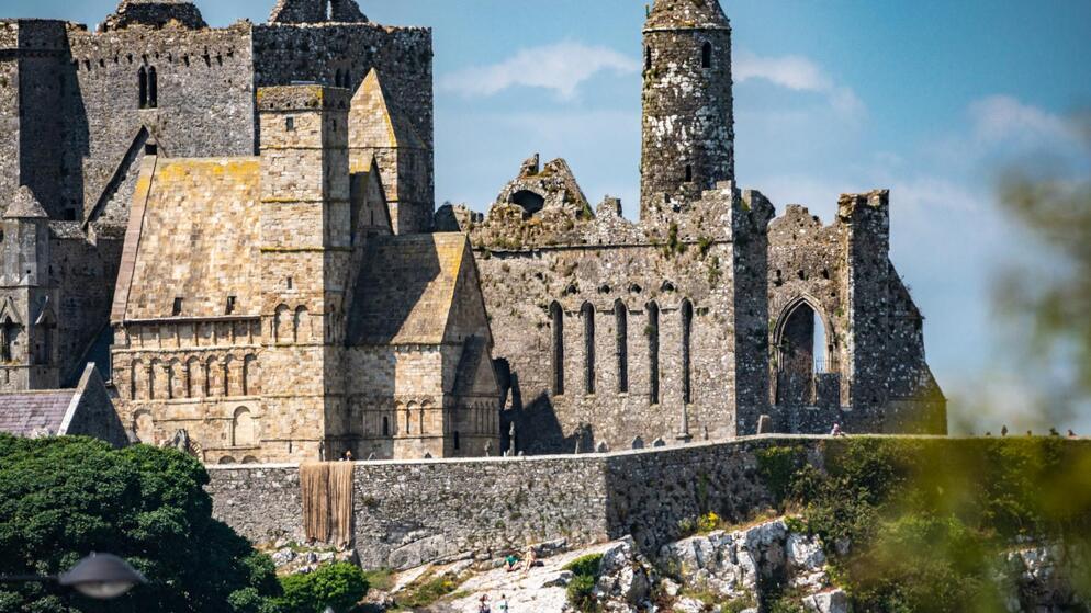Close-up of Cormac’s Chapel and medieval ruins at the Rock of Cashel under a clear blue sky.