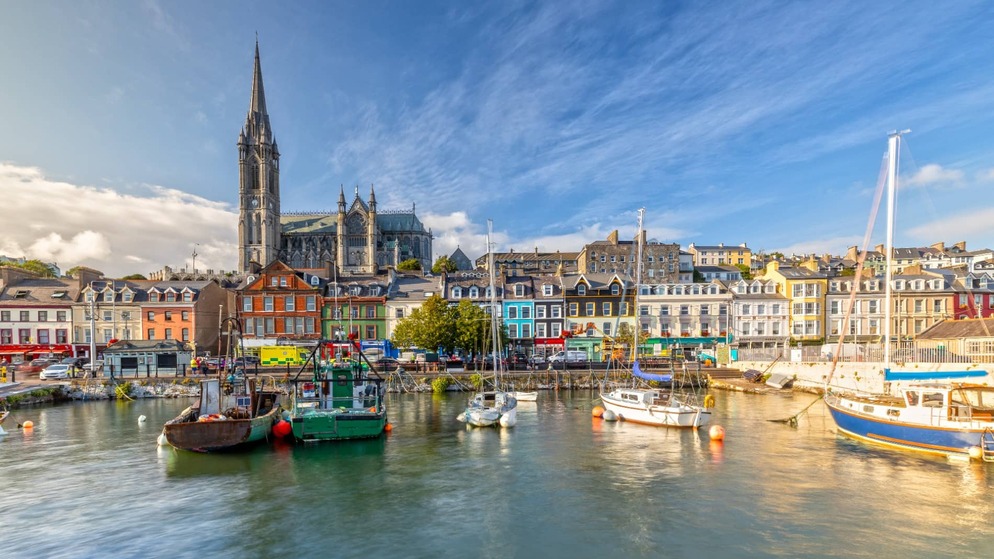 Les bâtiments colorés du front de mer et la cathédrale Saint-Colman à Cobh, dans le comté de Cork, vus depuis l'eau par une journée ensoleillée.