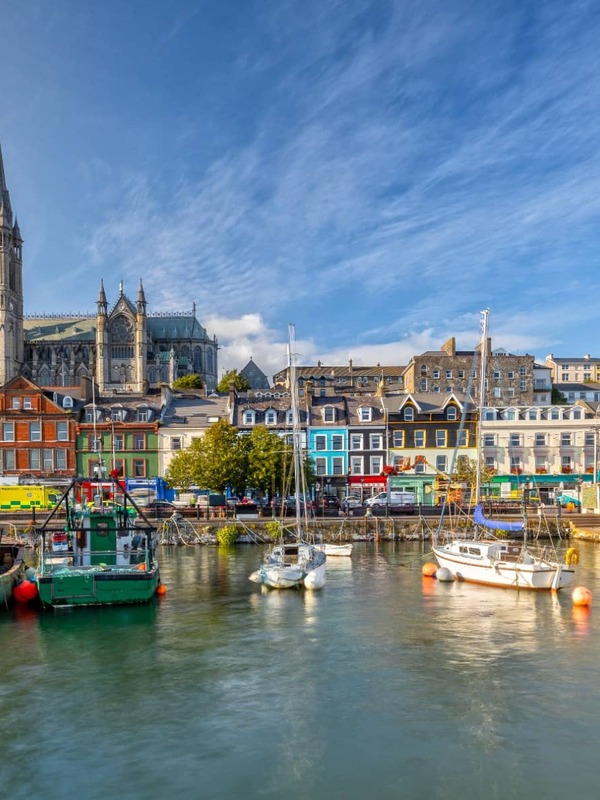 Colorati edifici sul porto e la Cattedrale di St Colman a Cobh, nella contea di Cork, visti dall'acqua in una giornata di sole.