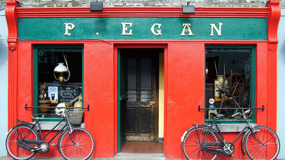 Red and green exterior of P. Egan pub with bicycles outside in County Offaly, Ireland.