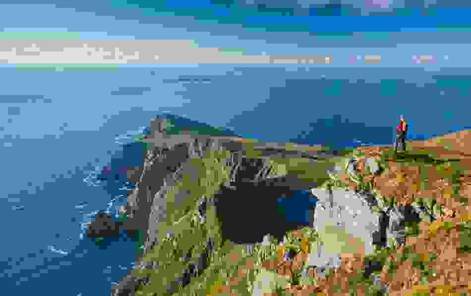 Spaziergänger stehen auf einer Klippe auf Achill Island mit einem Panoramablick auf die Klippen von Croaghaun, die Keem Bay und den atlantischen Ozean.