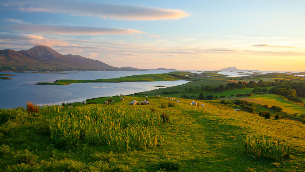 Panoramablick über die Drumlin-Inseln der Clew Bay in der Nähe von Westport, mit fernen Bergen, die hinter blauen Atlantikgewässern aufragen.