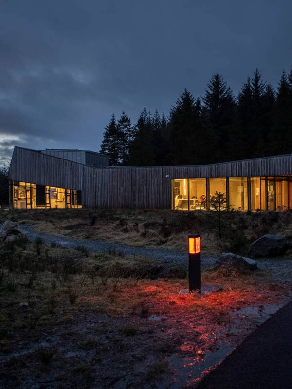 Il moderno OM Dark Sky Park &amp; Observatory, caldamente illuminato, di notte nella contea di Tyrone, circondato da una foresta sotto cieli bui.