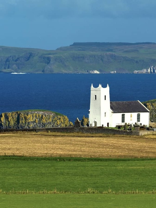 La chiesa di Ballintoy sulla costa della contea di Antrim, Irlanda del Nord, con vista sull'Oceano Atlantico e sull'isola di Rathlin.