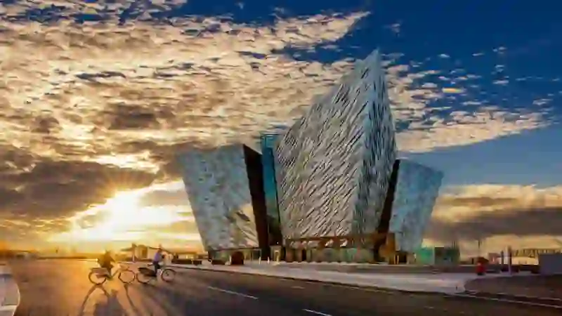 I ciclisti passano davanti al Titanic Belfast all'alba, sotto nuvole drammatiche a Belfast, nella contea di Antrim.