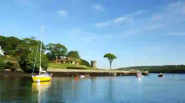 Boten aangemeerd op het rustige water van Strangford Lough, naast een door bomen omzoomde kustlijn in County Down.