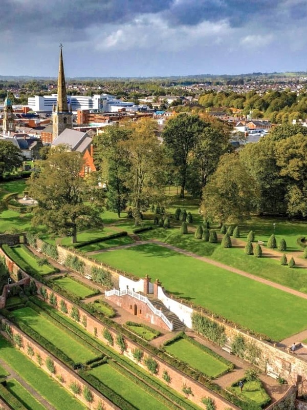 View over Lisburn city with Castle Gardens, historic churches and surrounding countryside under dramatic skies.