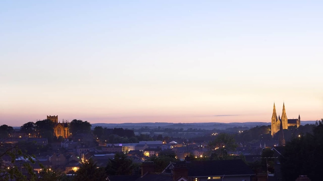 Armagh city skyline at dusk, with the twin St Patrick’s Cathedrals illuminated above the historic cityscape.