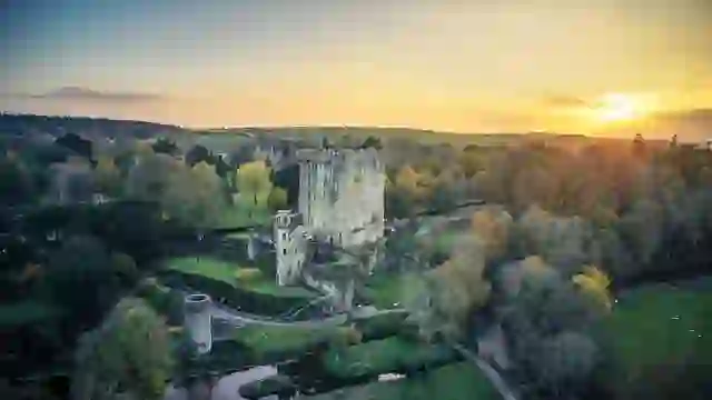 Blarney Castle and gardens, County Cork, with historic tower, river and lush woodland at sunset.