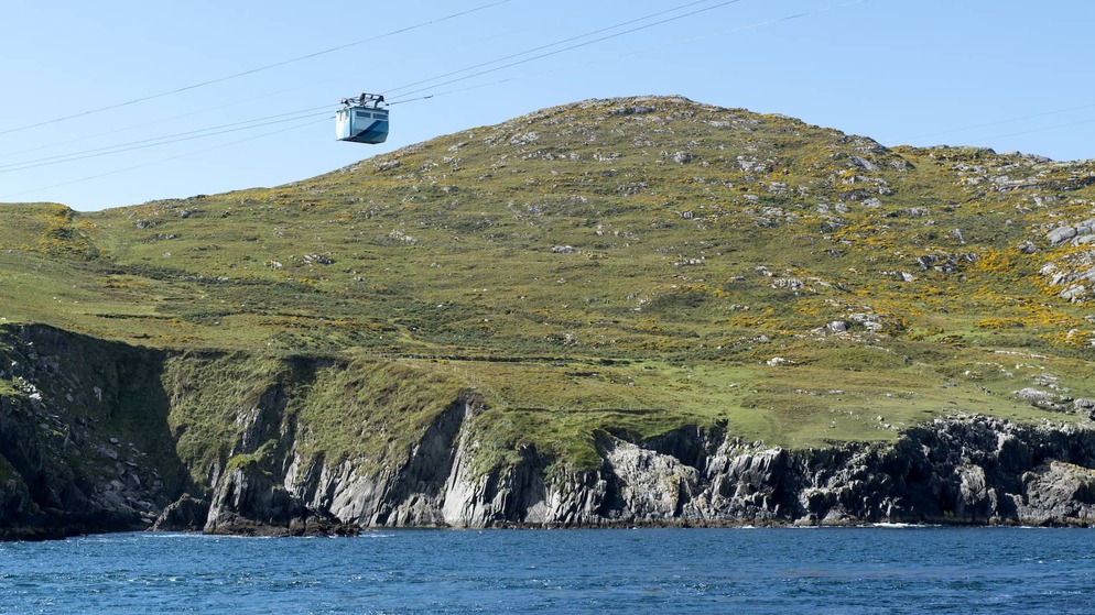 Dursey Island cable car over rugged coastline, West Cork, above Atlantic waters on clear day.