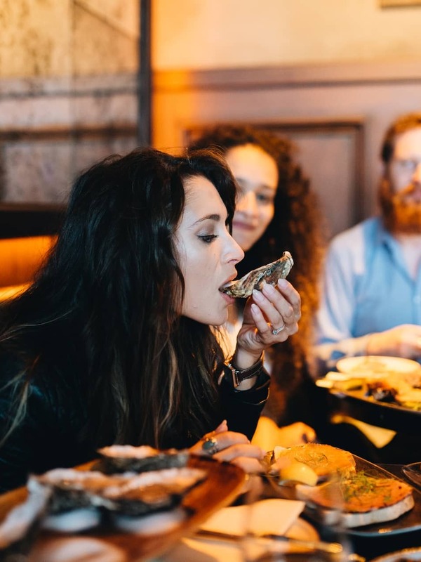 Mensen genieten van oesters en lokale gerechten in een restaurant in Cork, een illustratie van de vermaarde culinaire scene van de stad.