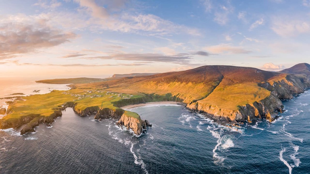 Vue aérienne de la plage de Silver Strand dans le comté de Donegal, entourée de falaises spectaculaires et de l’océan Atlantique.