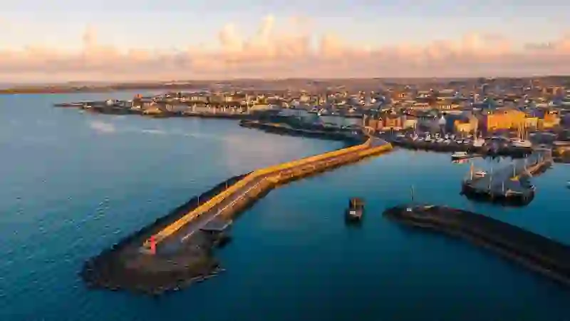 Luchtfoto van de haven van Bangor in County Down met jachthaven, promenade langs de zee en kalme kustwateren bij zonsondergang.
