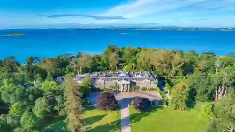 Luchtfoto van het landgoed Mount Stewart in County Down, omgeven door bossen en met uitzicht op Strangford Lough op een zonnige dag.