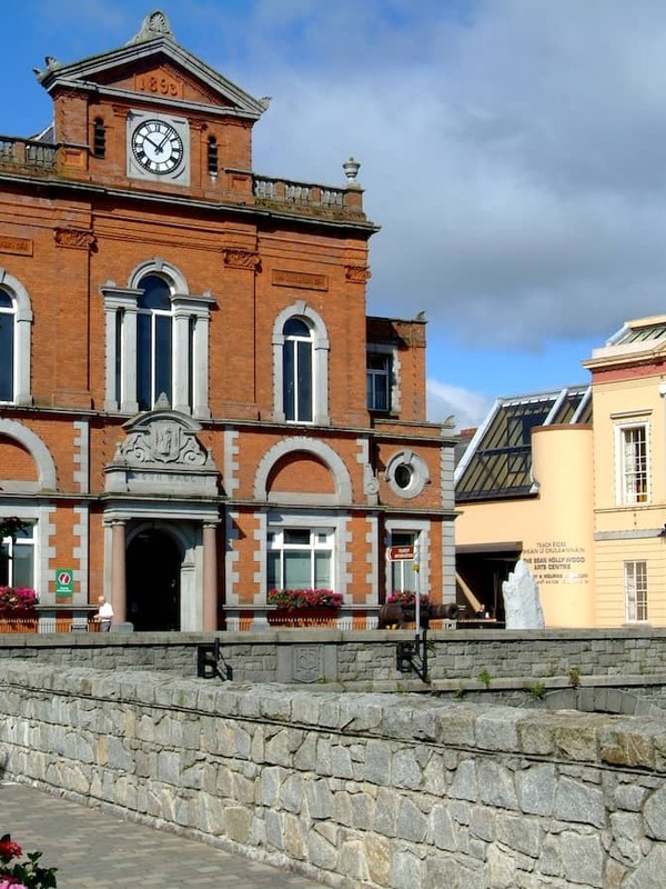 De historische Newry Town Hall naast het kanaal in county Down, met kleurrijke bloemen en een blauwe lucht.