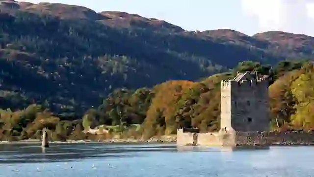 Narrow Water Castle beside Carlingford Lough, with wooded hills and mountain scenery in County Down.