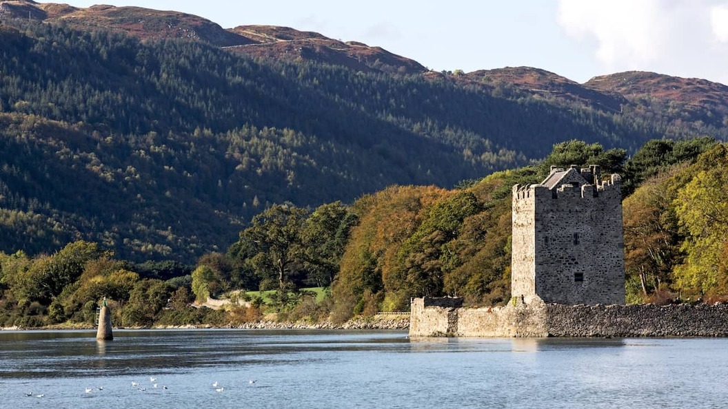 Narrow Water Castle beside Carlingford Lough, with wooded hills and mountain scenery in County Down.