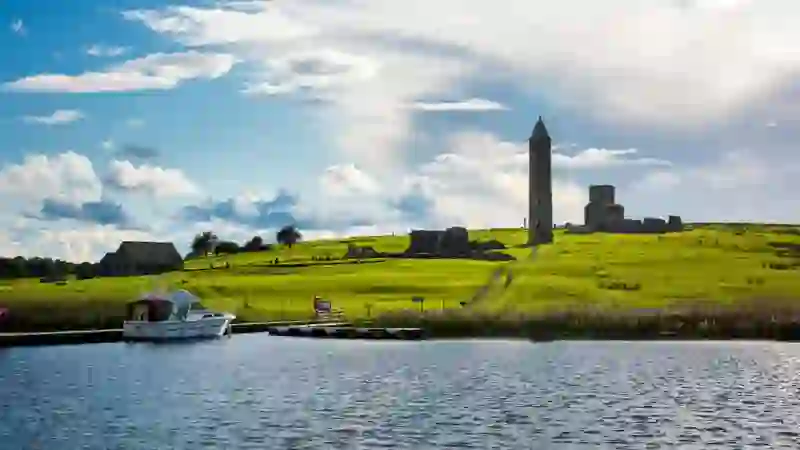 Boat moored beside Devenish Island round tower on Lower Lough Erne, County Fermanagh.