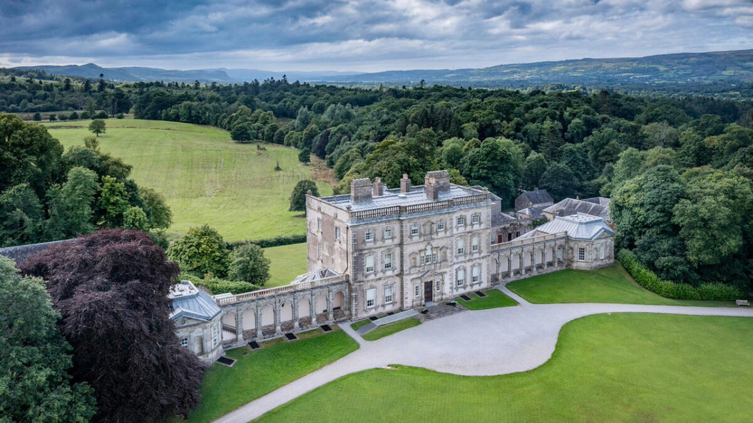 Vista aérea de la mansión y el parque de Florence Court, rodeado de bosques bajo el cielo del condado de Fermanagh.