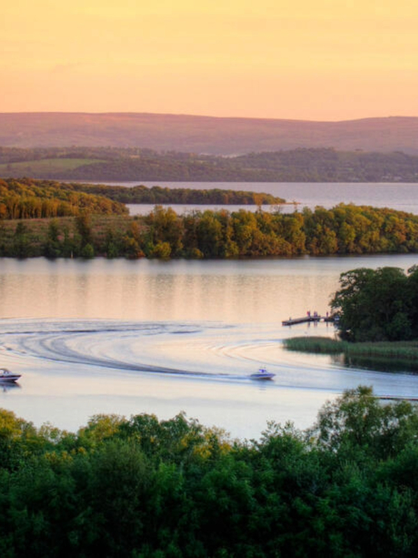 Motorboats leave curved wakes across the Fermanagh Lakelands at sunset in County Fermanagh.