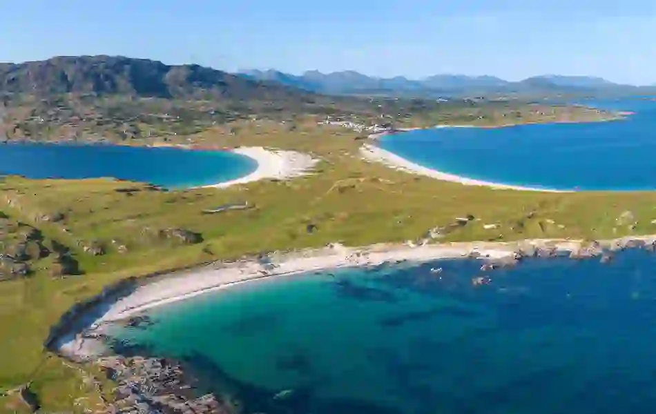Aerial view of a curved white-sand beach and turquoise waters along the Connemara coast in Galway.