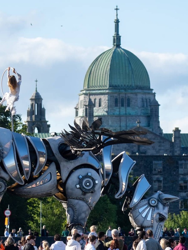 Large mechanical horse parade sculpture performing in Galway city with Galway Cathedral in the background.