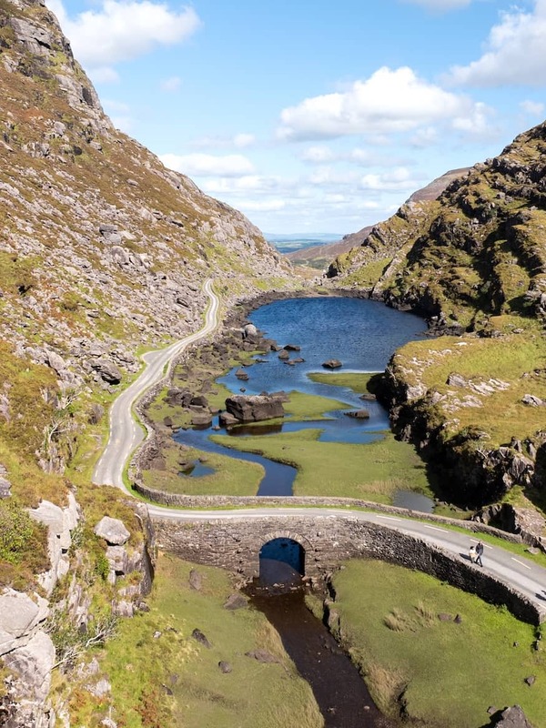 Aerial view of the Gap of Dunloe, with a winding road, stone bridge and mountain lake in County Kerry, Ireland.
