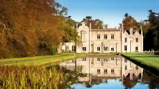 Kilruddery House reflected in a still pond, framed by autumn trees and manicured lawns in Bray, County Wicklow.