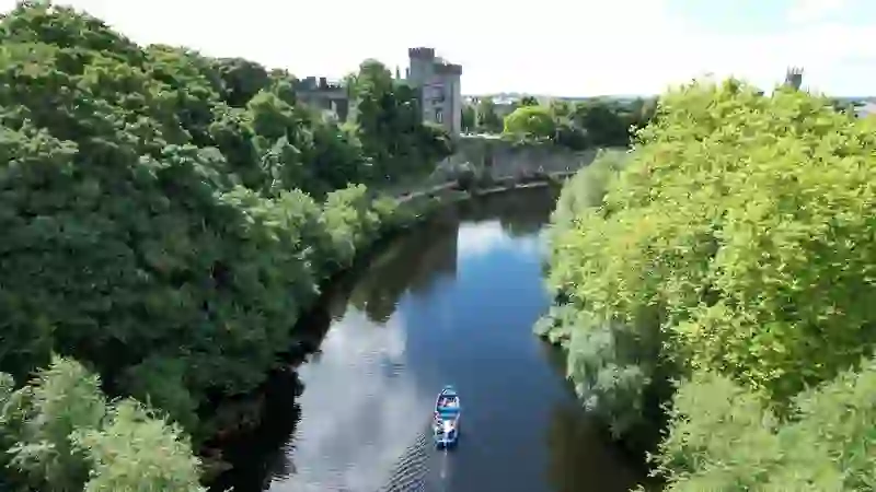 Excursion en bateau sur la rivière Nore avec vue sur le château de Kilkenny et ses berges verdoyantes.