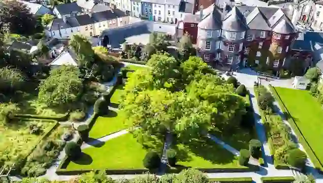 Vue aérienne des jardins du domaine de Butler House dans la ville de Kilkenny, avec des pelouses soignées, des allées et des maisons de ville historiques.