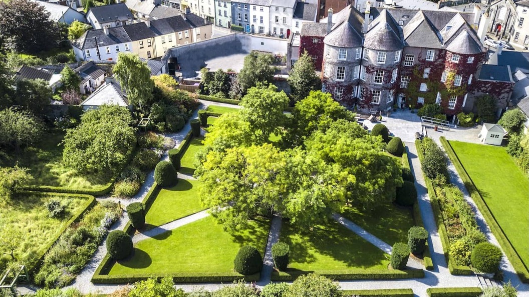Vue aérienne des jardins du domaine de Butler House dans la ville de Kilkenny, avec des pelouses soignées, des allées et des maisons de ville historiques.