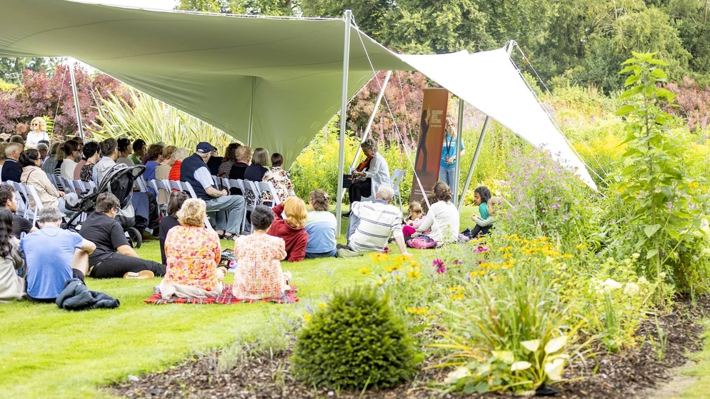 Audience enjoying live music at Kilkenny Arts Festival in a garden setting under a canopy.