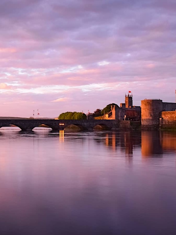 Château du Roi Jean et Thomond Bridge se reflétant dans les eaux du Shannon au crépuscule dans la ville de Limerick.