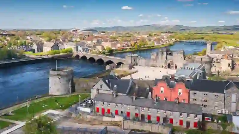 Aerial view of Limerick city with King John’s Castle, the River Shannon, and rows of colorful buildings.