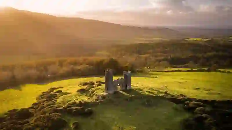 Aerial view of a historic stone tower house in the Ballyhoura countryside at sunset in County Limerick.