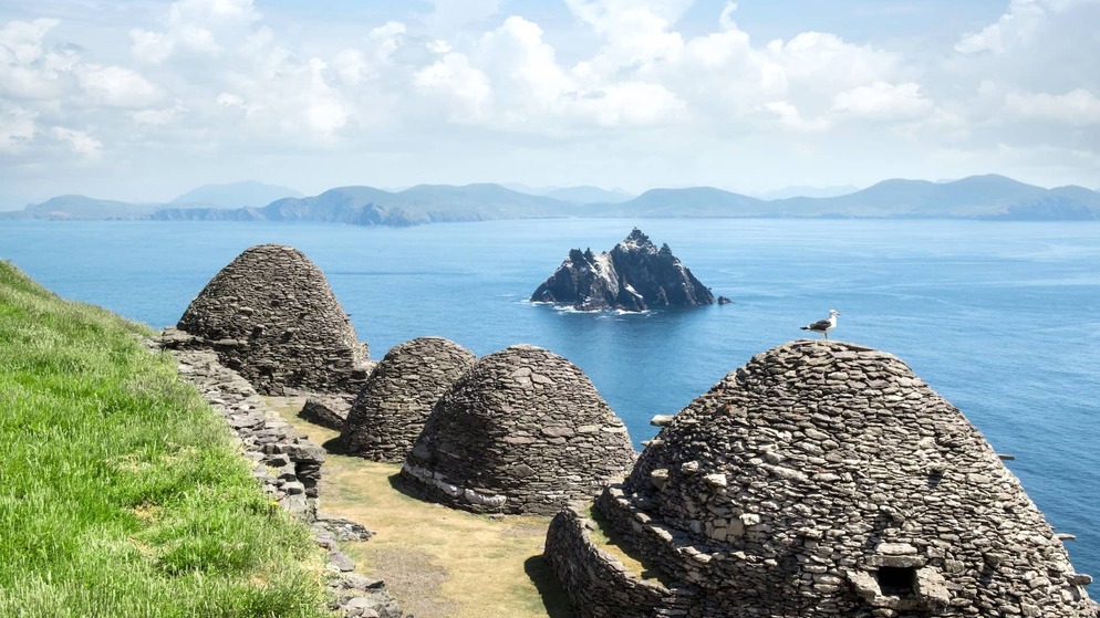 Stone beehive huts overlooking Skellig Michael and the Atlantic Ocean off the coast of County Kerry.