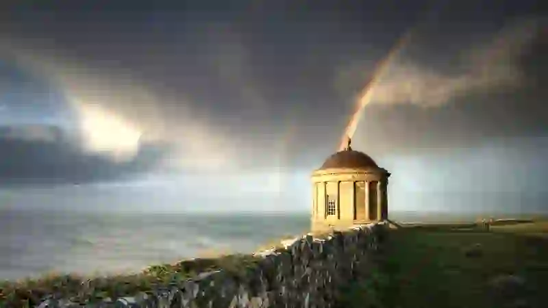 Mussenden Temple in der Grafschaft Londonderry, eingerahmt von einem doppelten Regenbogen über imposanten Küstenklippen.