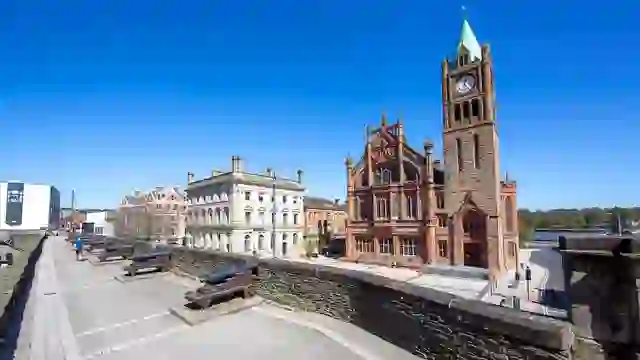 Historische Kanonen säumen die Stadtmauern von Derry mit Blick auf das Rathaus und das Stadtzentrum in Derry~Londonderry.