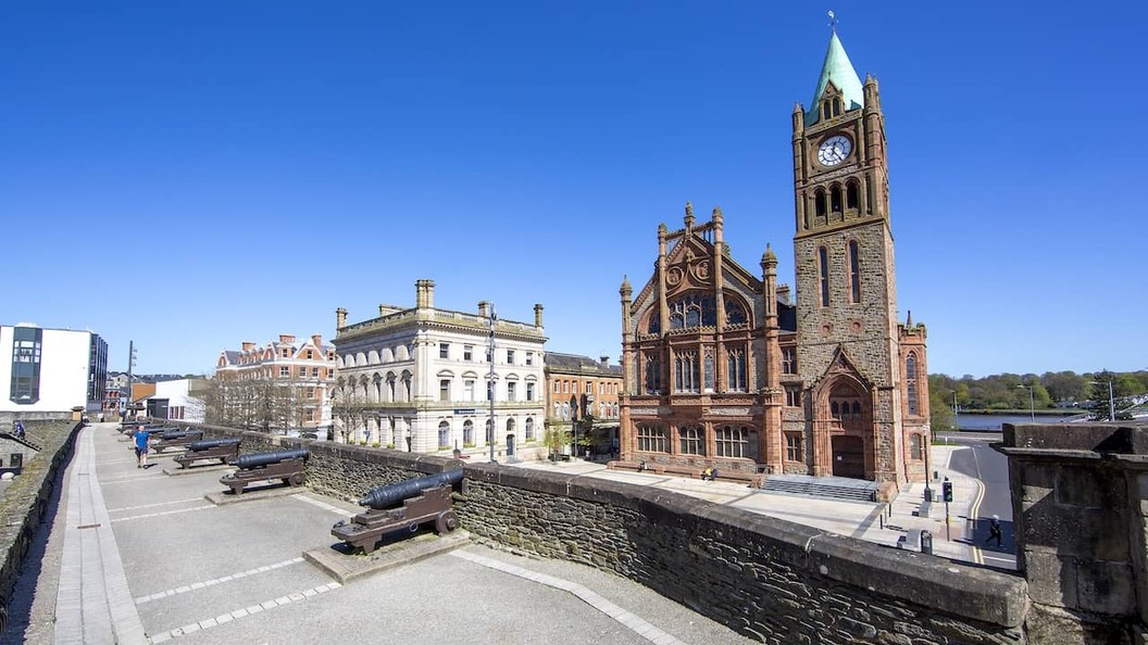 Historische Kanonen säumen die Stadtmauern von Derry mit Blick auf das Rathaus und das Stadtzentrum in Derry~Londonderry.