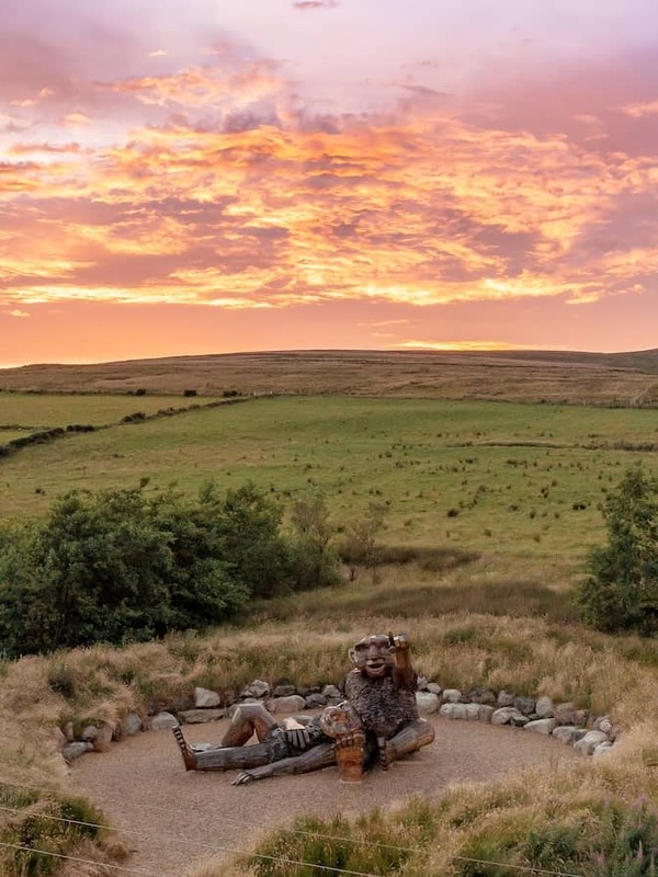 Holzskulptur von Riesen in den Sperrin Mountains der Grafschaft Tyrone mit Blick auf die hügelige Landschaft bei Sonnenuntergang.