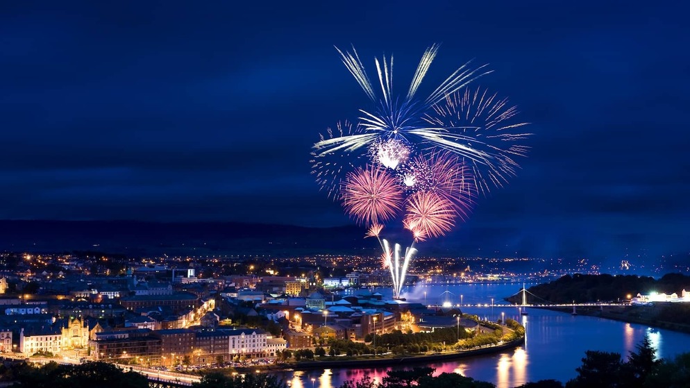 Fireworks light up the River Foyle during Derry Halloween celebrations at night.