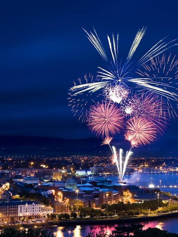 Fireworks light up the River Foyle during Derry Halloween celebrations at night.