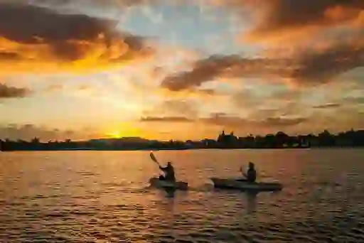 Two people kayaking on Lough Derg at sunset with orange skies over County Tipperary.