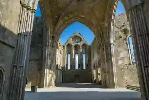 Interior view of the Rock of Cashel ruins in County Tipperary, showing Gothic arches and stone walls in sunlight.